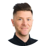 Sam Demma Portrait of Sam Demma, a man with short, styled brown hair, light skin, and a trimmed beard, wearing a black collared shirt. Elite Speaker Coaching expert, posed against a white background. Elite Speaker Coaching