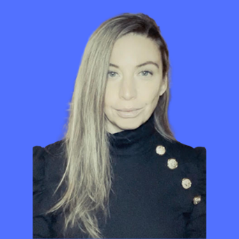 Sam Demma A woman with long, straight blonde hair wearing a black top with decorative buttons poses confidently in front of a solid blue background, embodying the professionalism of Elite Speaker Coaching by Sam Demma. Elite Speaker Coaching